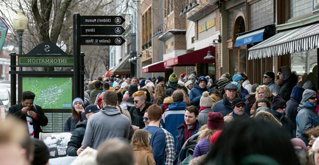 A crowd of people fill the sidewalks of Saratoga Springs, NY